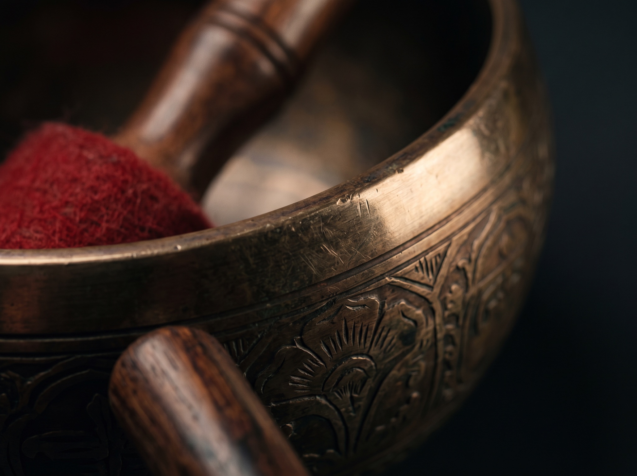 Macro detail of engraved bronze, felt mallet fibers, and aged wood in warm reflected light